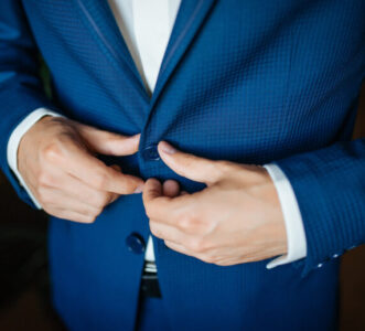 wedding preparation groom buttoning his blue jacket before wedding